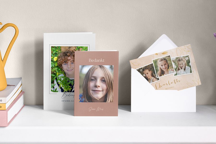 Gepersonaliseerde eerste heilige communie bedankkaarten van albelli voor jongens en meisjes op een wandplank.