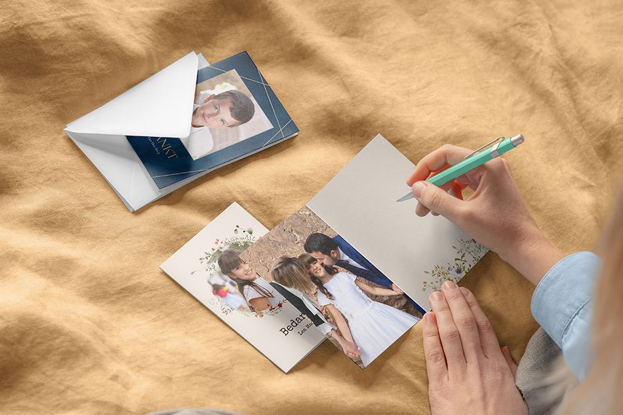 Iemand die nadenkt over wat te schrijven op een communiekaart met verschillende gepersonaliseerde communiekaarten van albelli.