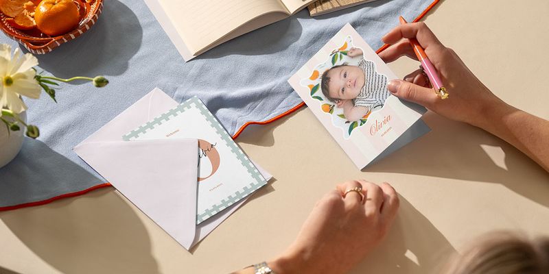 Een vrouw schrijft een felicitatie geboorte kaart voor een dochter en zoekt naar de juiste geboorte wensen op kaart van albelli.