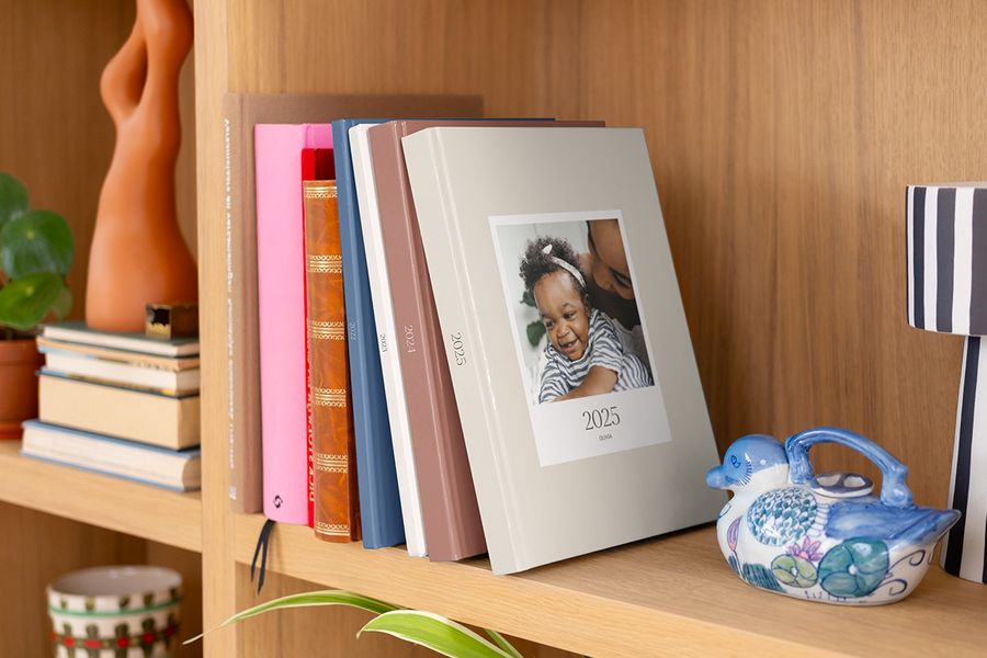 Een rij kleurrijke, van patronen voorziene albelli Jaarboeken netjes uitgestald in een boekenkast.