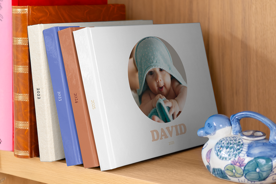 Een reeks fotoboeken van verschillende jaren, zoals een baby fotoboek eerste jaar, gerangschikt in een boekenkast.