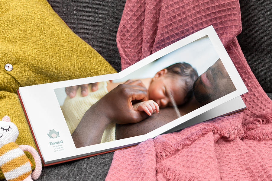 Een vader die zijn pasgeboren baby vasthoudt in een open mijn eerste jaar fotoboek met de geboortegegevens van de baby.