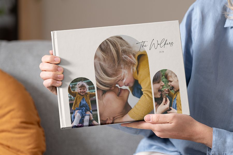 Een familie fotoboek dat wordt vastgehouden, met verschillende foto's op de omslag, perfect voor het toevoegen van fotoboek quotes en quotes voor in fotoboeken.