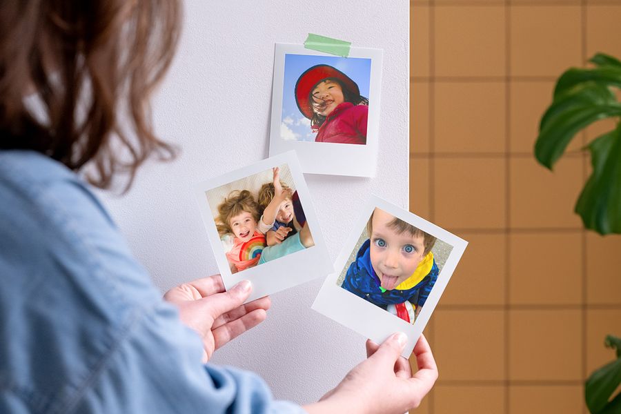 Een vrouw houdt gepersonaliseerde albelli fotoafdrukken vast, als inspiratie voor kinderfeest bedankjes en vulling voor kinderfeest tasjes.