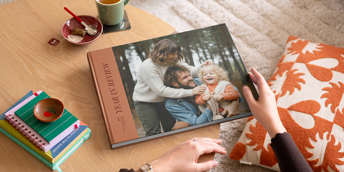 Een albelli koffietafelboek met een jaaroverzicht en een mooie familiefoto op de omslag, liggend op een salontafel als inspiratie voor een gepersonaliseerd koffietafelboek.