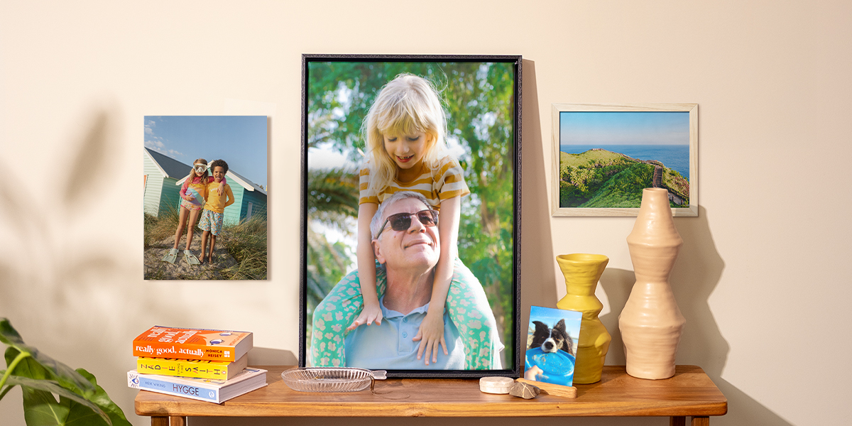Een selectie albelli fotoafdrukken verspreid door het huis, met een hondenfoto op een bijzettafel, een poster van kinderen aan de muur en twee ingelijste foto’s, als inspiratie voor foto’s aan de muur en een frisse lente-look in huis.