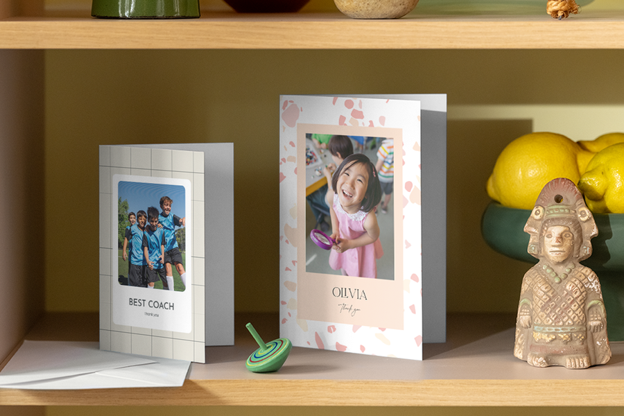 Twee verschillende gepersonaliseerde albelli bedankkaartjes voor leerkrachten staan op een plank in huis.