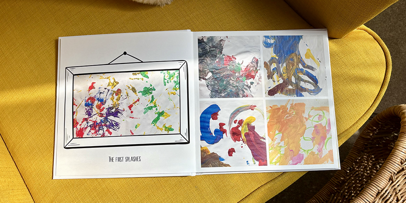 Een geopend kinderfotoboek ligt op een gele fauteuil, met op de linkerpagina de eerste verfspetters van jonge kinderen en op de rechterpagina vier verschillende schilderijen, ter illustratie van albelli's ideeën voor een kinderfotoboek.