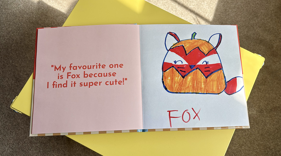 Een geopend kinderfotoboek toont links een bijschrift en citaat van een kind dat haar kunstwerk uitlegt, met daarnaast haar bijbehorende tekening van een cartoonvos, ter illustratie van albelli's tips voor het toevoegen van tekst aan een kinderfotoboek.