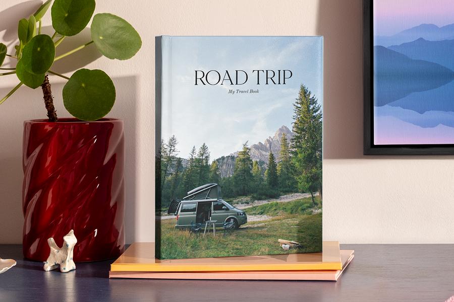 Een groot staand fotoboek toont een foto van een camper in een bergachtig, nationaal-parkachtig landschap, ter illustratie van albelli's fotoalbum titel ideeën voor een roadtrip.