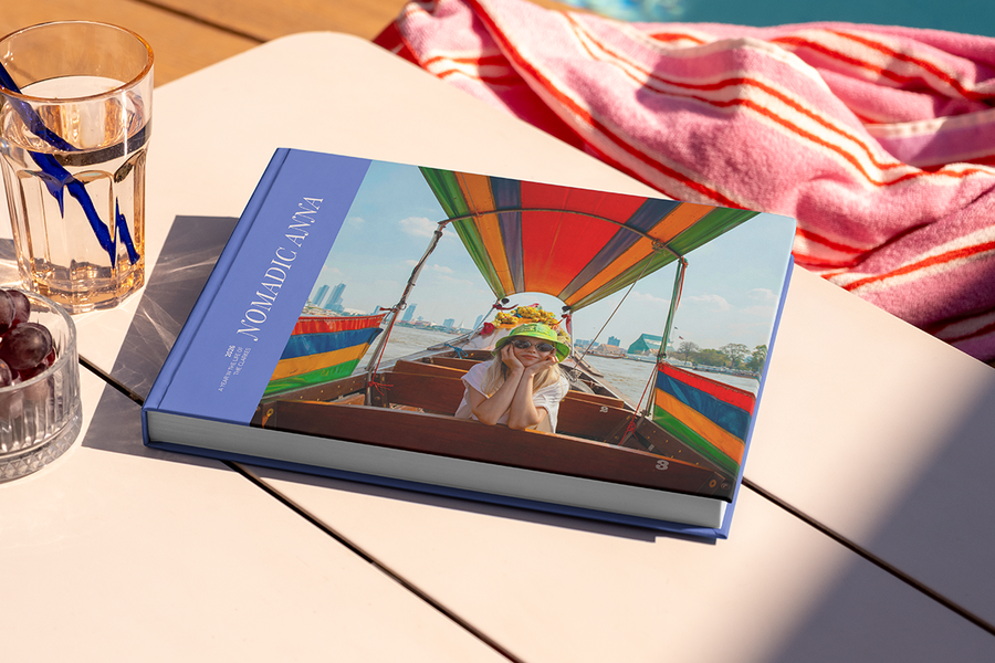 Een groot liggend reisfotoboek met de titel 'Nomadic Anna' ligt op een tafel, met op de cover een foto van een meisje op reis, ter illustratie van albelli's fotoalbum titel ideeën voor reizen.