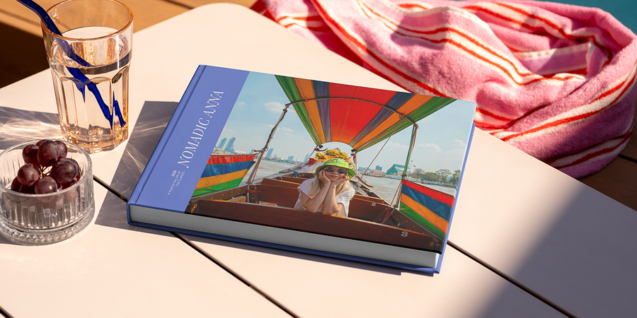 Een groot liggend reisfotoboek met de titel 'Nomadic Anna' ligt op een tafel, met op de cover een foto van een meisje op reis, ter illustratie van albelli's fotoalbum titel ideeën voor reizen.