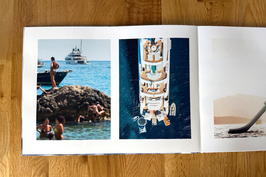 Een geopende spread uit het fotoboek van Charl van Rooy toont vakantiebeelden aan het strand, met mensen die relaxen bij de zee en een jacht, ter illustratie van de visuele flow van zijn fotografieportfolio.