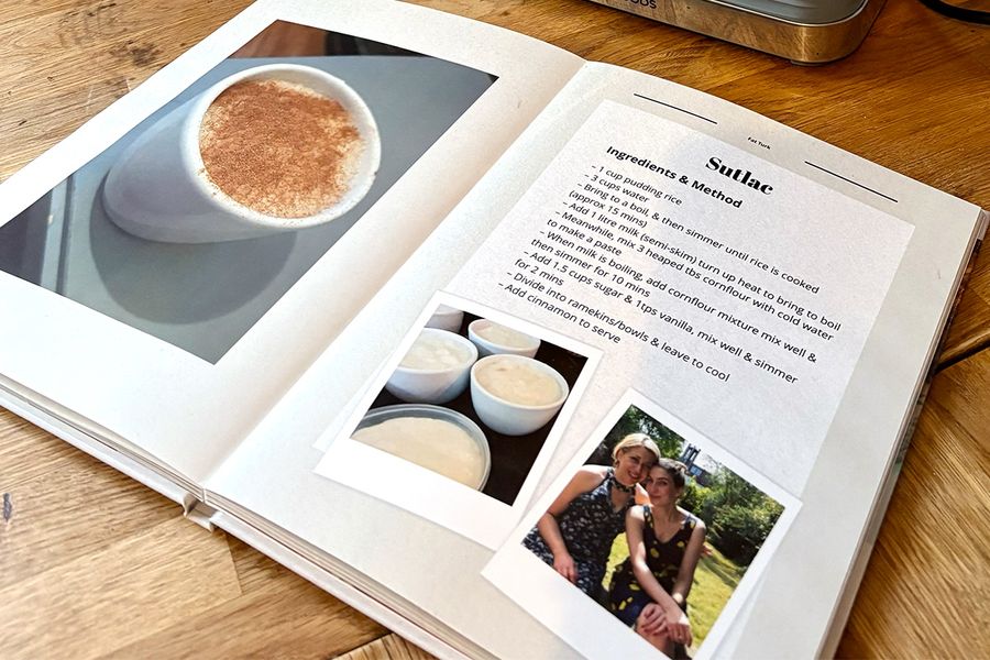 Sarah's geopende kookboek ligt op het keukenblad en toont het layflat-formaat, met afbeeldingen van Turkse rijstpudding op de linkerpagina en het bijbehorende familierecept op de rechterpagina, ter illustratie van albelli's tip om een layflat-ontwerp te kiezen dat makkelijk te gebruiken is tijdens het koken.