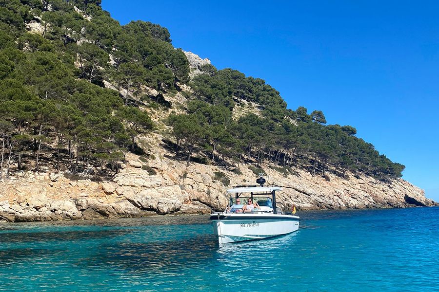 Een koppel zit op een boot bij een prachtige ruige kustlijn op Ibiza, als beeld van de rustigere, relaxte kant van een septembervakantie op het eiland.