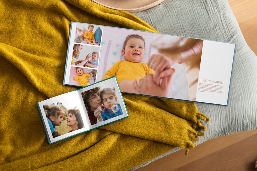 Twee gepersonaliseerde fotoboeken liggen opengeslagen met familiefoto's, rustend op een mosterdgele plaid, ter illustratie van hoe albelli fotoboeken passen in een hygge-huis.