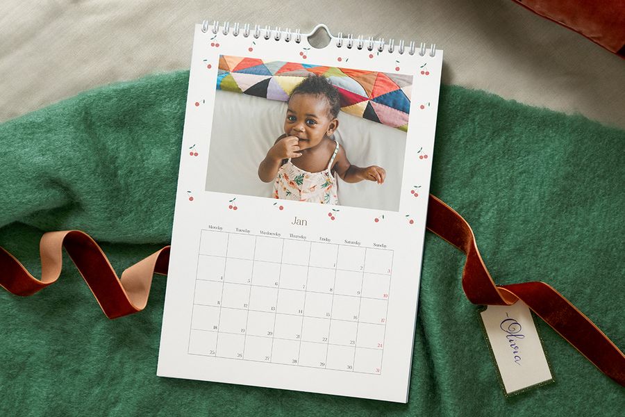 Gepersonaliseerde fotokalender met een foto van een baby in een zomerjurkje, ter illustratie van albelli’s ideeën om een gepersonaliseerde kalender te maken voor de eerste kerst van een baby.