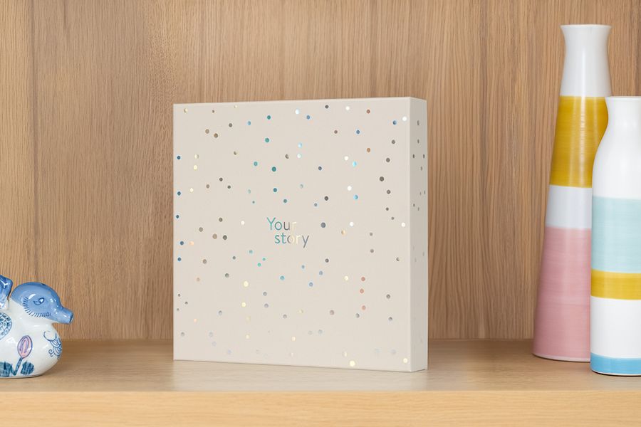 De presentatiedoos staat op een plank naast een vaas en snuisterijen, ter illustratie van hoe deze ook dient als een aantrekkelijke opbergdoos voor fotoalbums.