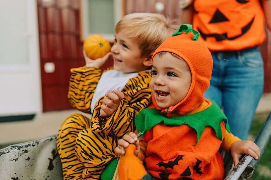Twee kinderen in Halloween-verkleedkleding, één verkleed als pompoen en één als tijger, ter illustratie van albelli's schattige Halloween-teksten voor Instagram.