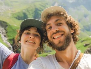 Een glimlachend stel in een heuvelachtig landschap tijdens een zomeravontuur, ideaal voor bijschriften voor zomerfoto's op Instagram of in een albelli fotoboek.