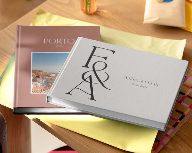 Twee gepersonaliseerde fotoboeken in verschillende formaten en ontwerpen op een tafel.
