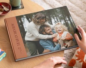 Een albelli koffietafelboek met een jaaroverzicht en een mooie familiefoto op de omslag, liggend op een salontafel als inspiratie voor een gepersonaliseerd koffietafelboek.