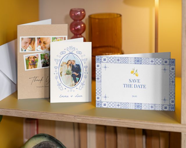 Drie trouwfotokaarten op een plank: één save-the-date en twee bedankkaarten.
