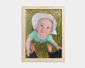 Poster in houten lijst met foto van een baby en een sinaasappel.